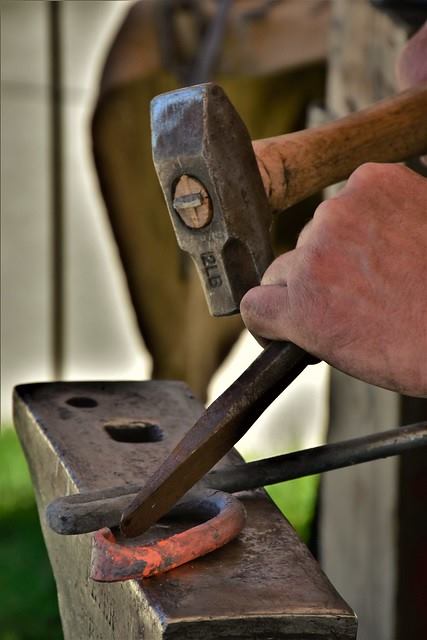 A Blacksmith at the Baker City annual Miner's Jubilee uses a blacksmith chisel not to punch a hole, but to shape a piece of work. Image source