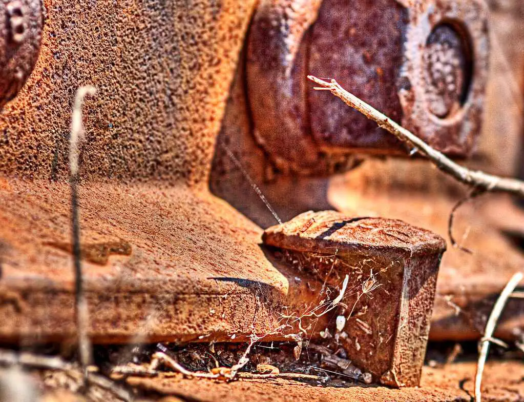 A rusty dog head Railroad spike holds down a piece of track Image Source