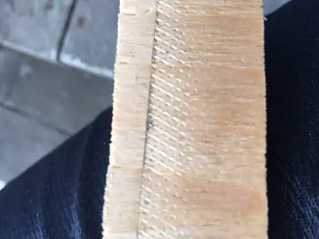 A piece of cedar board that has been imprinted by the serrated jaw of a metal working vise